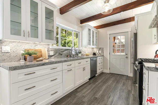 a kitchen with granite countertop white cabinets and white appliances with wooden floor