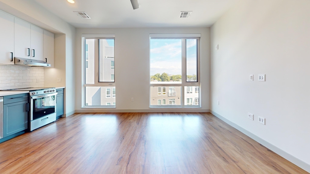 80 Rugg Road, Unit 1227 Boston, MA 02134 - Photo 3 of 13 a view of a kitchen and an empty room with wooden floor and a window