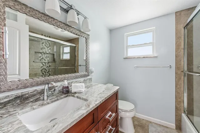 a bathroom with a granite countertop toilet sink and mirror