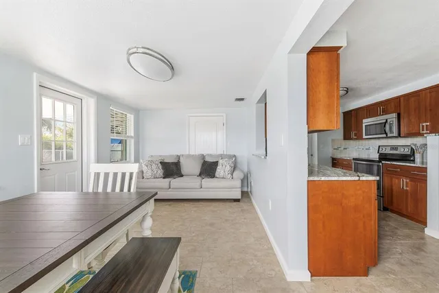 a living room with stainless steel appliances furniture and a kitchen view