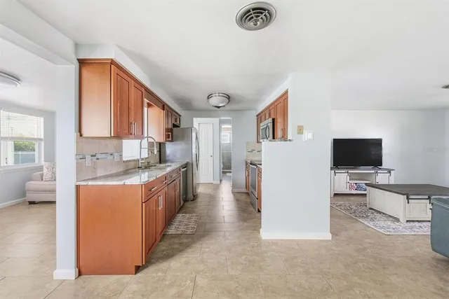 a large living room with stainless steel appliances granite countertop a couch and a flat screen tv