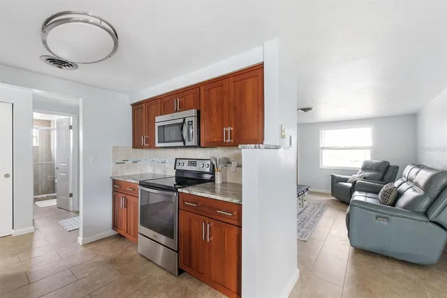 a living room with stainless steel appliances granite countertop furniture a sink a stove and a window