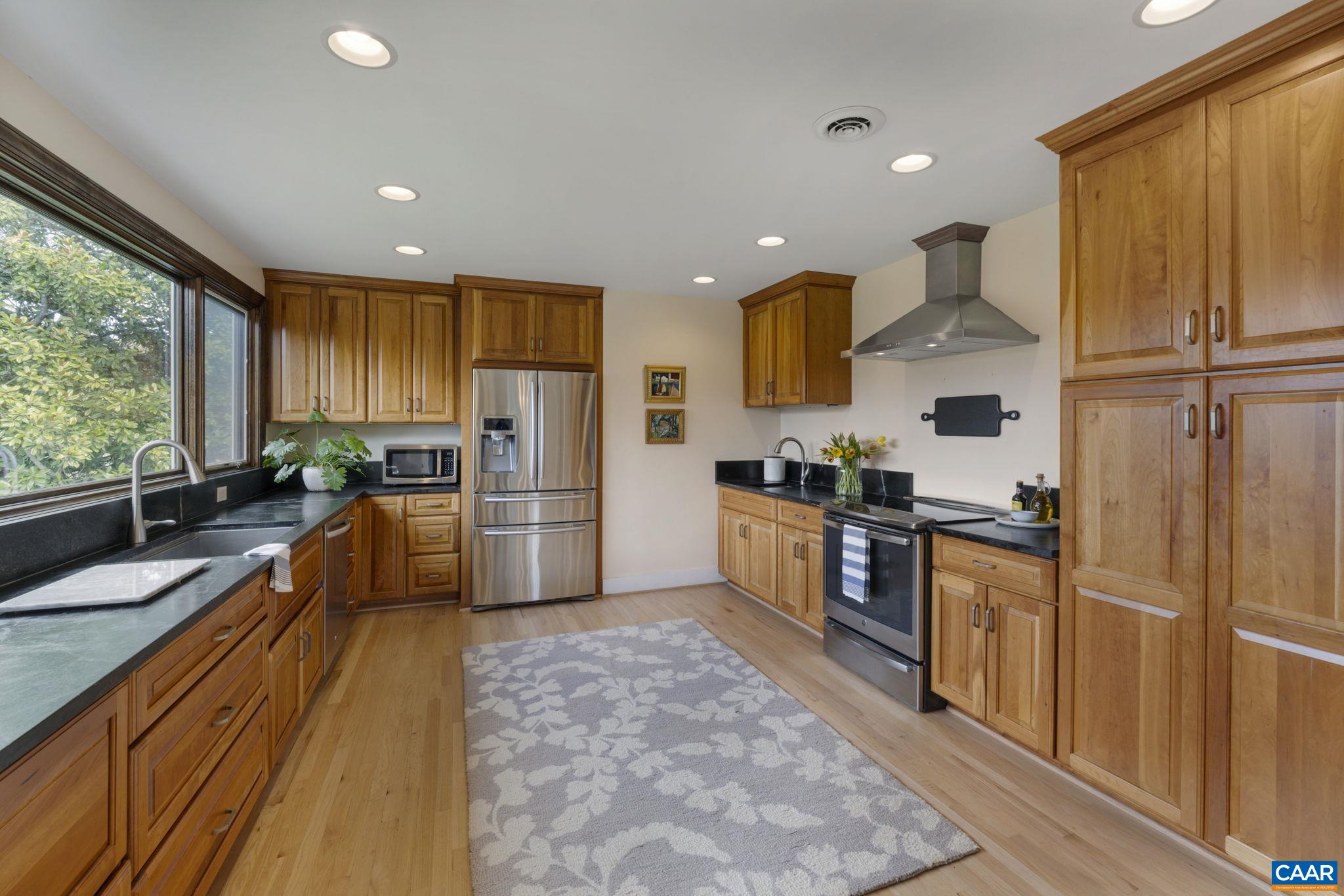 570 Rodes Drive Charlottesville, VA 22903 - Photo 16 of 75 a kitchen with stainless steel appliances granite countertop a refrigerator a stove top oven a sink dishwasher and wooden cabinets with wooden floor