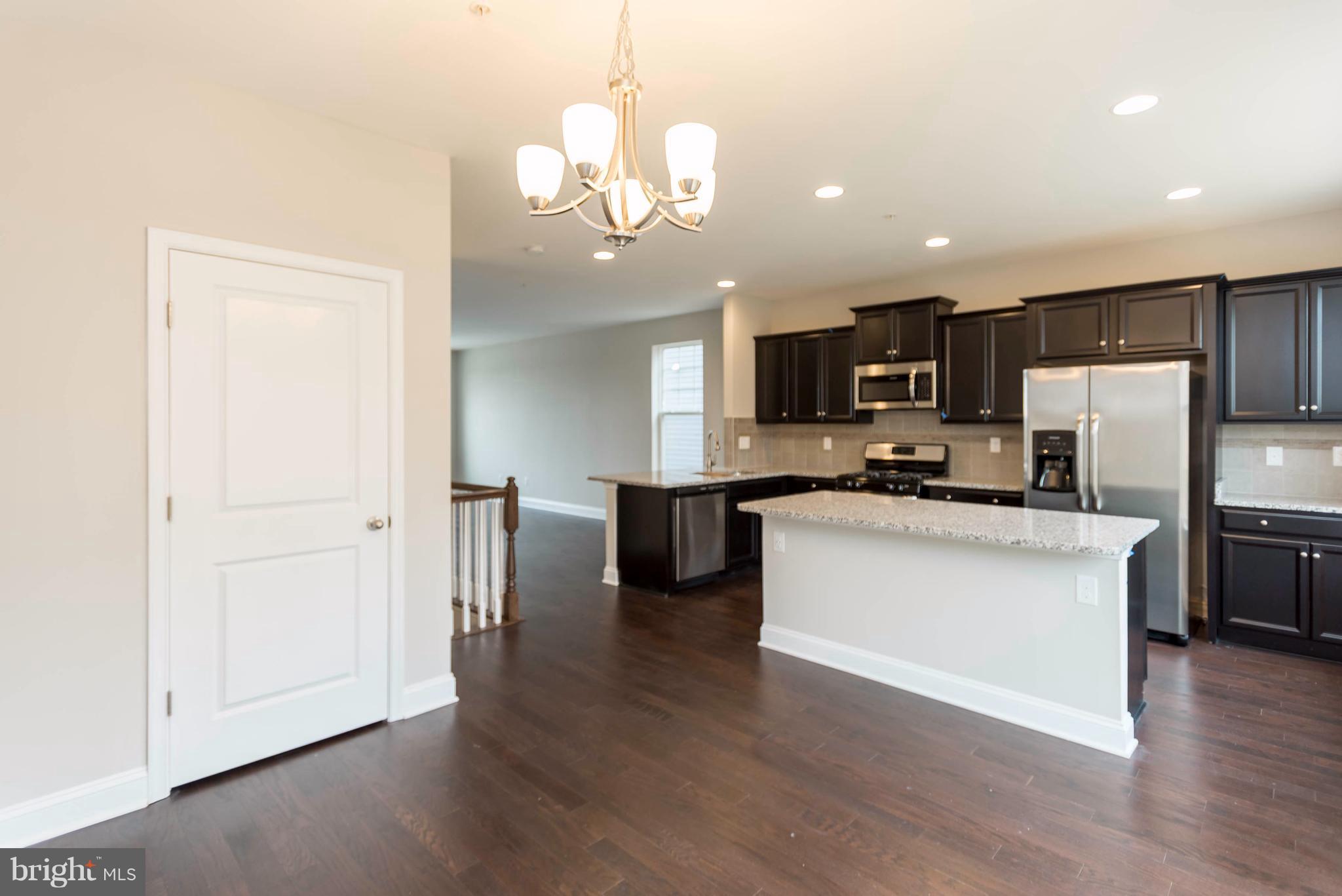 4609 Cambria Road Frederick, MD 21703 - Photo 3 of 29 a kitchen with stainless steel appliances granite countertop a refrigerator a sink dishwasher a oven and a dining table with wooden floor