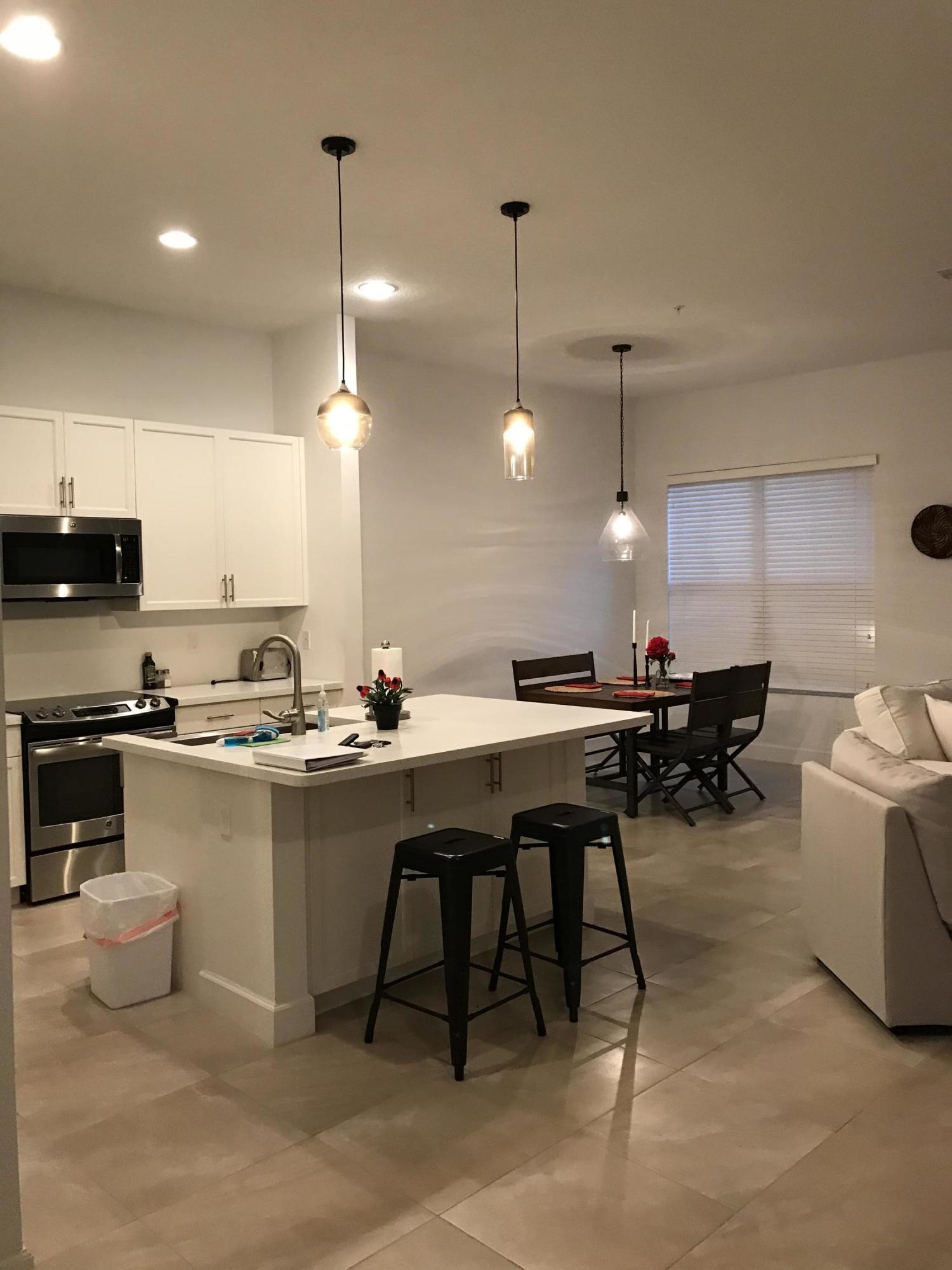 23045 Clear Echo Drive, Unit 76 Boca Raton, FL 33433 - Photo 5 of 35 a kitchen with a dining table chairs sink and stove