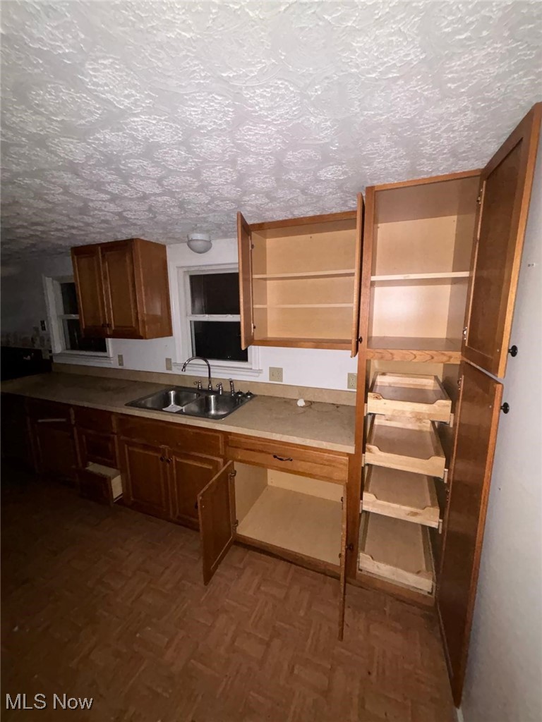 Kitchen featuring a textured ceiling, open shelves, and a sink