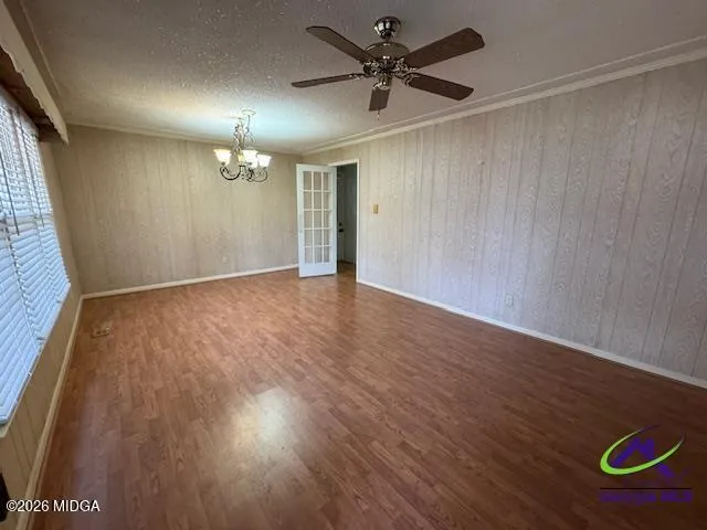 an empty room with wooden floor chandelier fan and windows