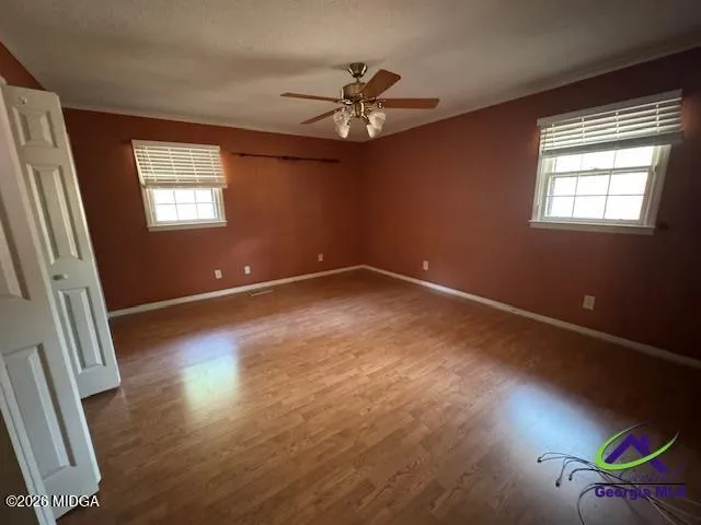 an empty room with wooden floor and windows