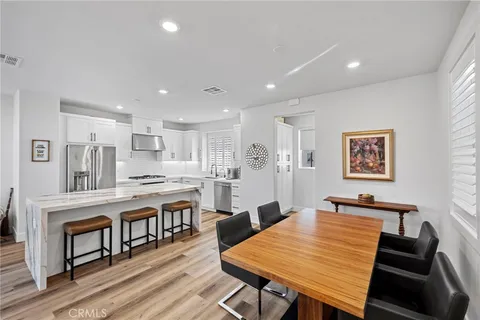 a kitchen with stainless steel appliances granite countertop a sink a stove a refrigerator and white cabinets