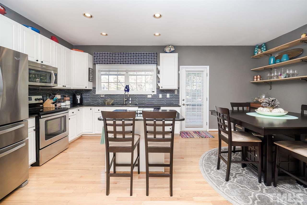 4714 Longhill Lane Raleigh, NC 27612 - Photo 5 of 19 a kitchen with stainless steel appliances kitchen island granite countertop a table chairs sink and cabinets