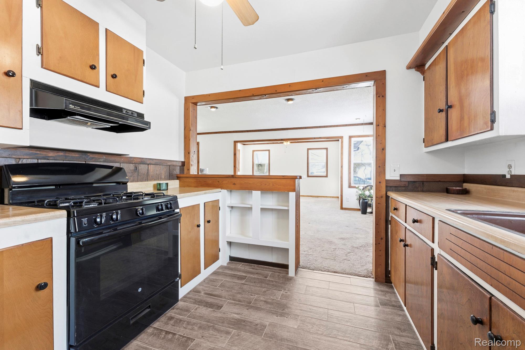 3375 Grant Road Rochester, MI 48309 - Photo 14 of 28 Kitchen with black gas range, a ceiling fan, light countertops, wood finish floors, and wood finish cabinetry