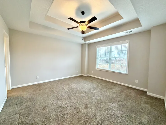 an empty room with ceiling fan and windows