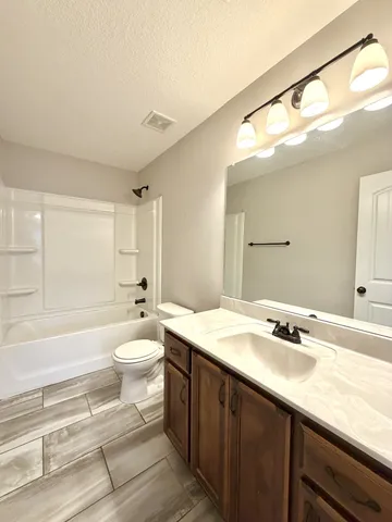 a bathroom with a granite countertop sink mirror vanity and toilet