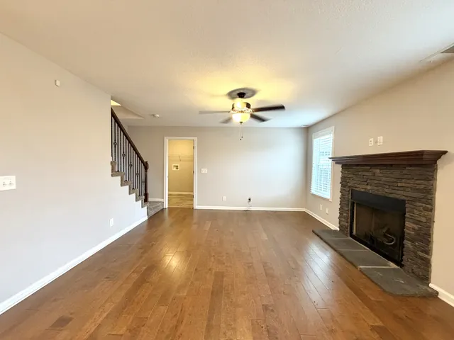 a view of an empty room with wooden floor fireplace and a window