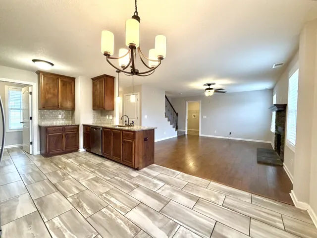 a kitchen with stainless steel appliances granite countertop a sink dishwasher a stove a refrigerator and a dining table with wooden floor