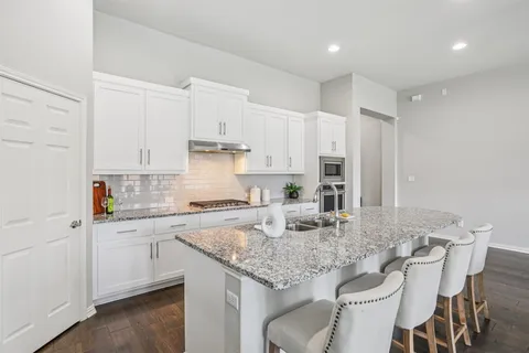 a kitchen with kitchen island granite countertop a white cabinets and chairs