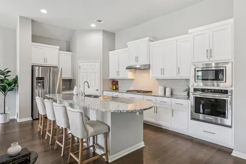 a kitchen with stainless steel appliances granite countertop a white cabinets and a stove top oven