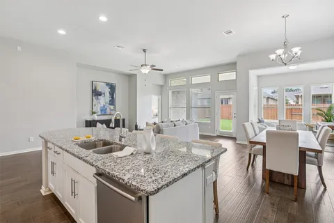a kitchen with granite countertop kitchen island stainless steel appliances a sink and living room view