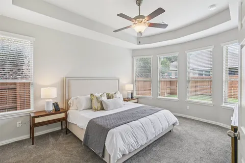 a bedroom with a large bed and a chandelier fan
