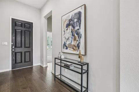 a view of a hallway with wooden floor and paintings on the wall