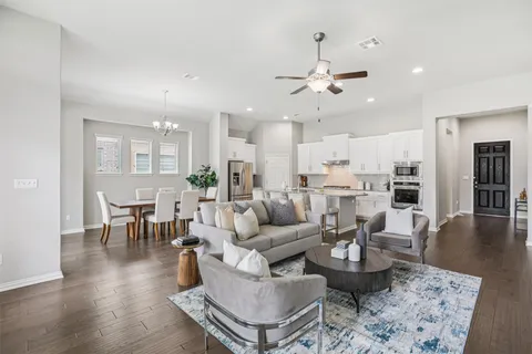 a living room with couches kitchen view and a dining table with wooden floor