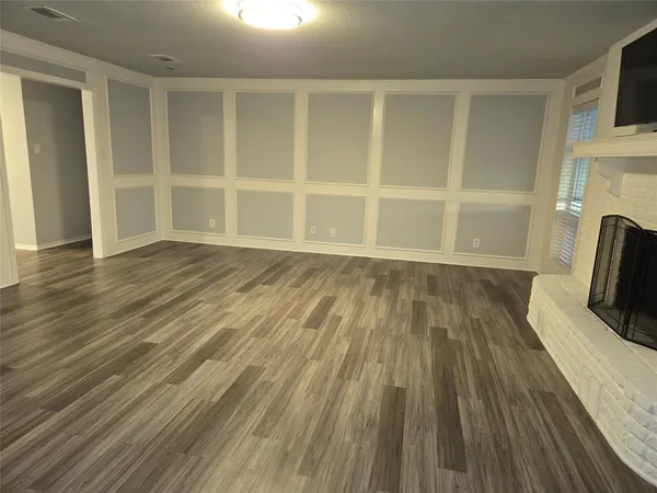 a view of empty room with wooden floor and fireplace