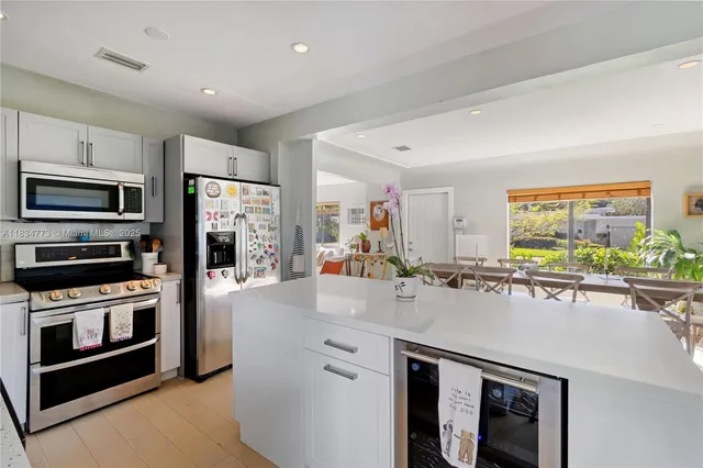a kitchen with stainless steel appliances a stove a sink a microwave a refrigerator and white cabinets