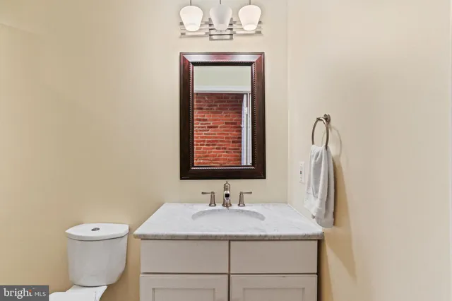 a bathroom with a granite countertop sink toilet and mirror