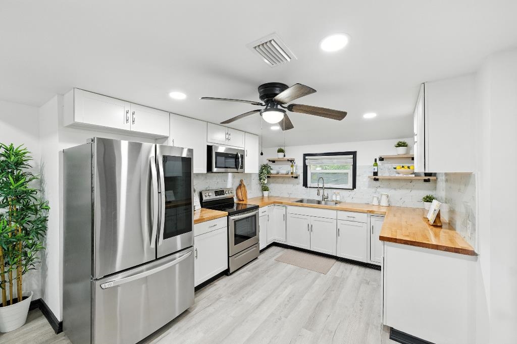 1637 Starratt Road Jacksonville, FL 32218 - Photo 24 of 44 a kitchen with white cabinets and stainless steel appliances