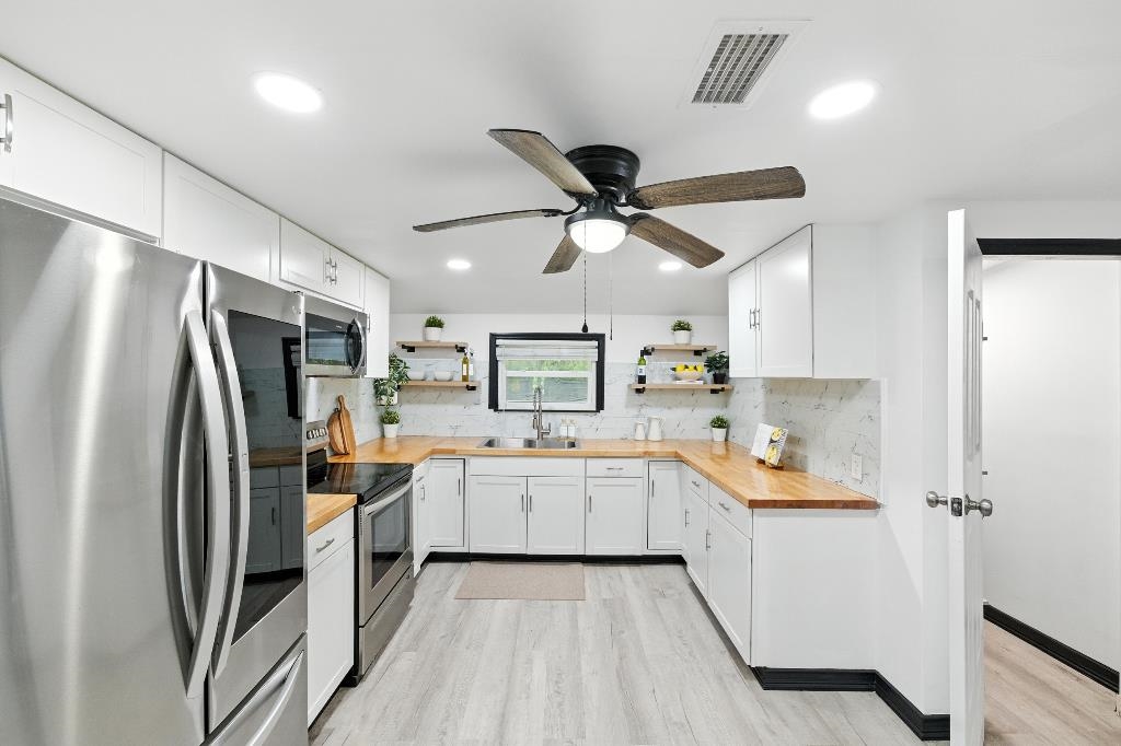 1637 Starratt Road Jacksonville, FL 32218 - Photo 25 of 44 a kitchen with white cabinets and stainless steel appliances