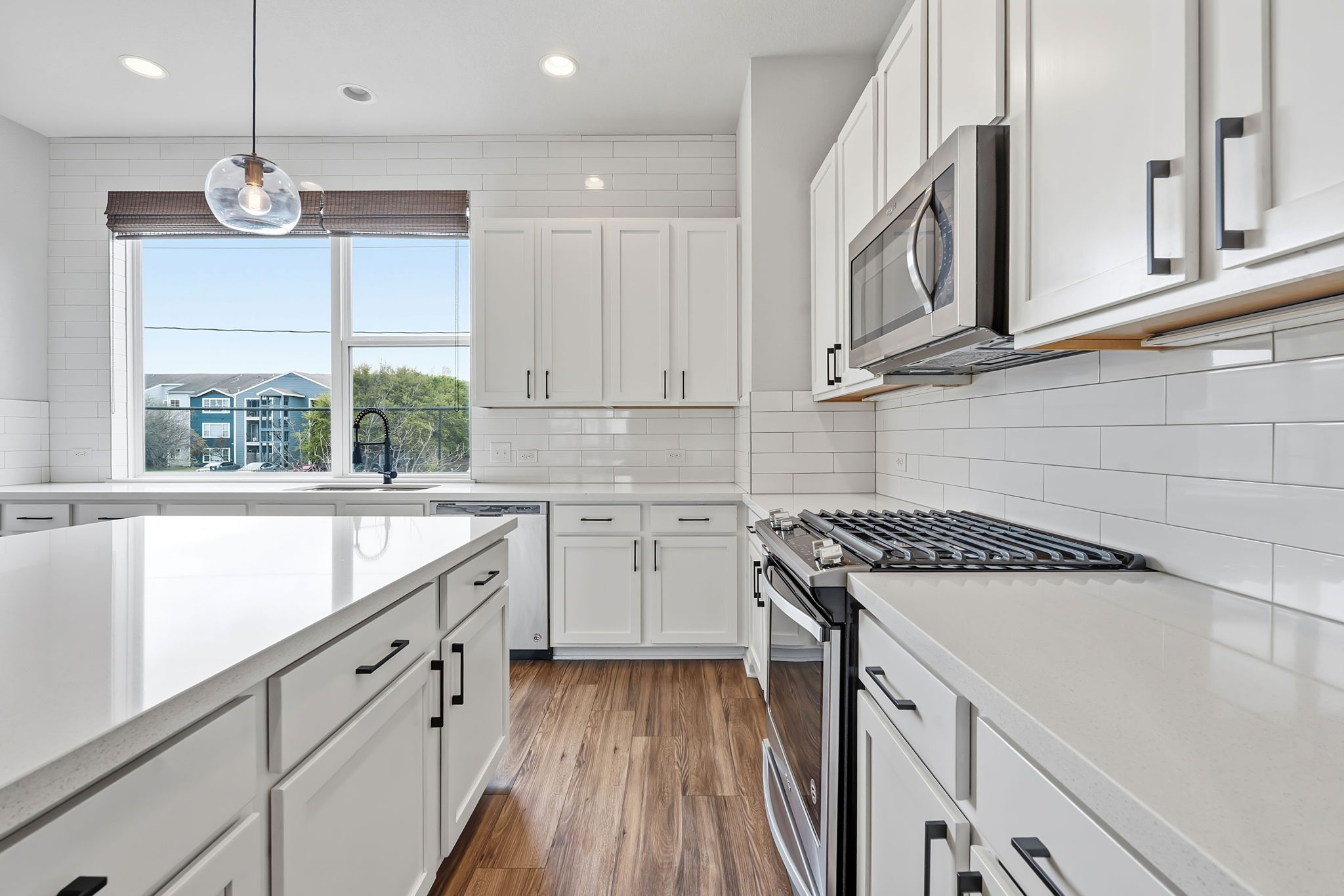 4409 Festival Path, Unit 26 Austin, TX 78741 - Photo 14 of 24 Kitchen with stainless steel appliances, white cabinets, dark wood-style flooring, light stone counters, and hanging light fixtures