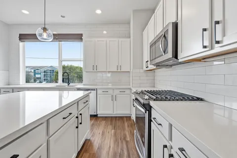 a kitchen with stainless steel appliances granite countertop a sink a stove and a wooden floors