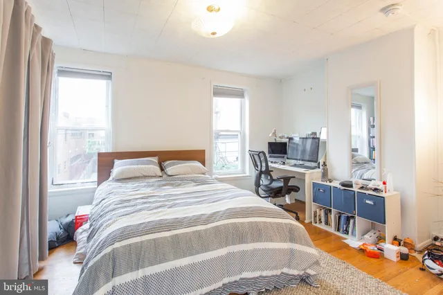 a bedroom with a bed a dresser and a large window