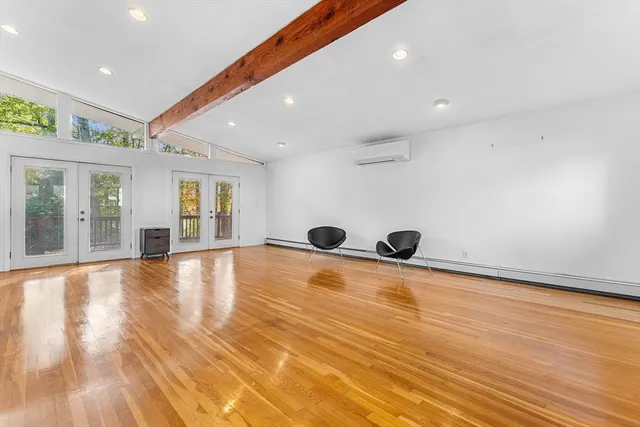 a view of an empty room with window and wooden floor