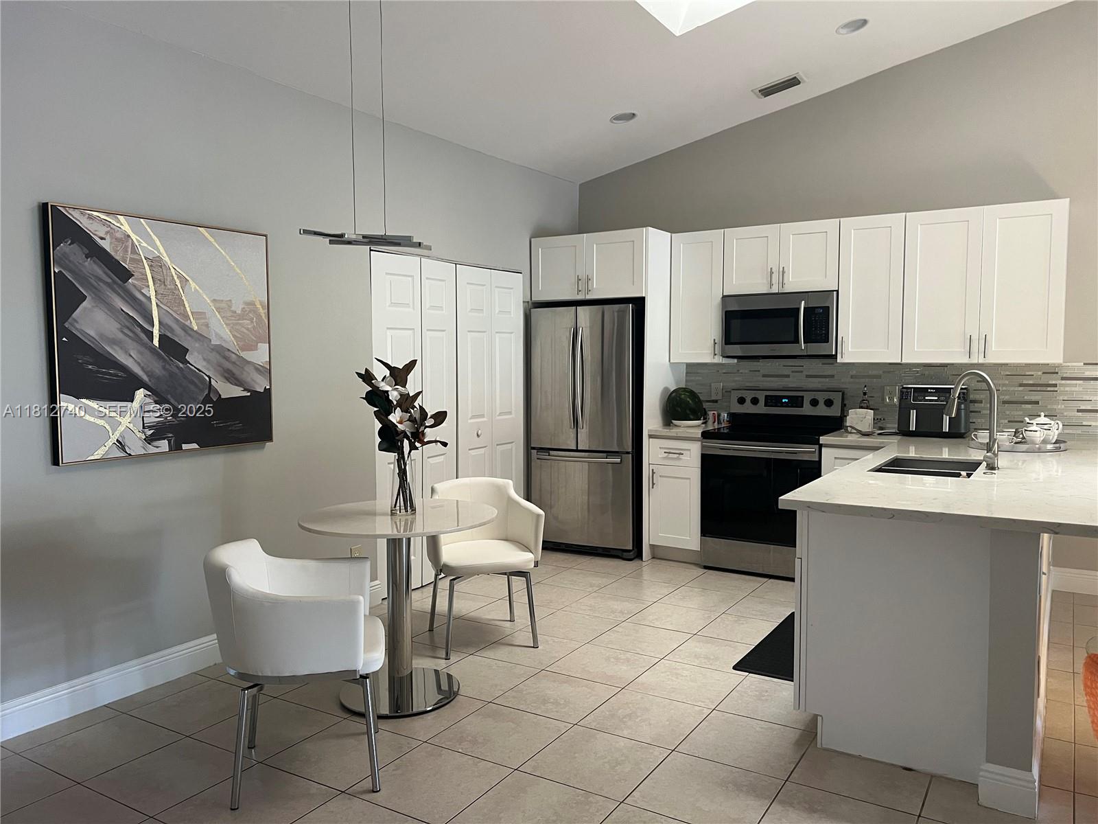 18428 Vía Di Regina, Unit 18428 Boca Raton, FL 33496 - Photo 4 of 6 a kitchen with stainless steel appliances a refrigerator sink and stove
