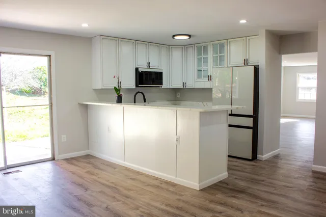 a kitchen with stainless steel appliances granite countertop a refrigerator a sink a stove a microwave and wooden floors