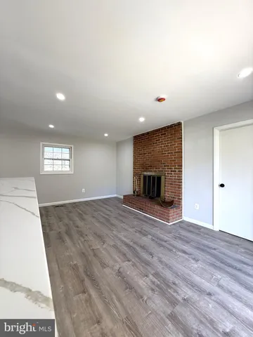 a view of empty room with wooden floor and fireplace