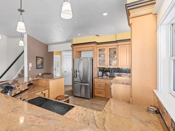 a room with stainless steel appliances kitchen island granite countertop a refrigerator and cabinets