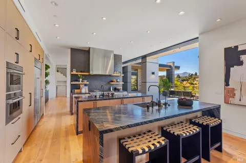 a kitchen with stainless steel appliances granite countertop a stove a sink dishwasher a refrigerator and a dining table with wooden floor