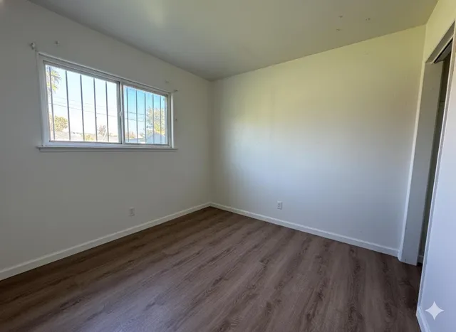 a view of an empty room with wooden floor and a window