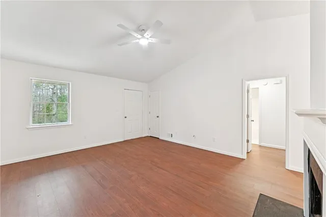 an empty room with wooden floor and a ceiling fan
