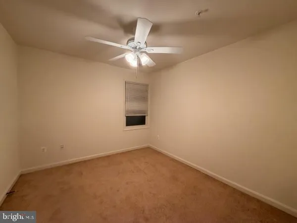 an empty room with a chandelier fan and windows
