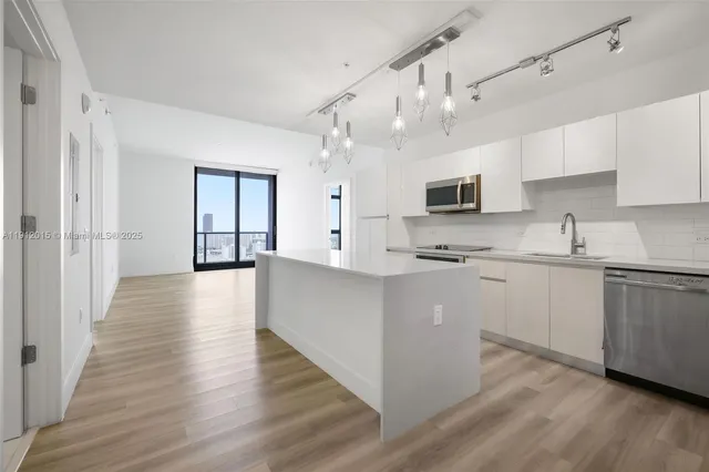 a kitchen with kitchen island granite countertop a sink cabinets and wooden floor