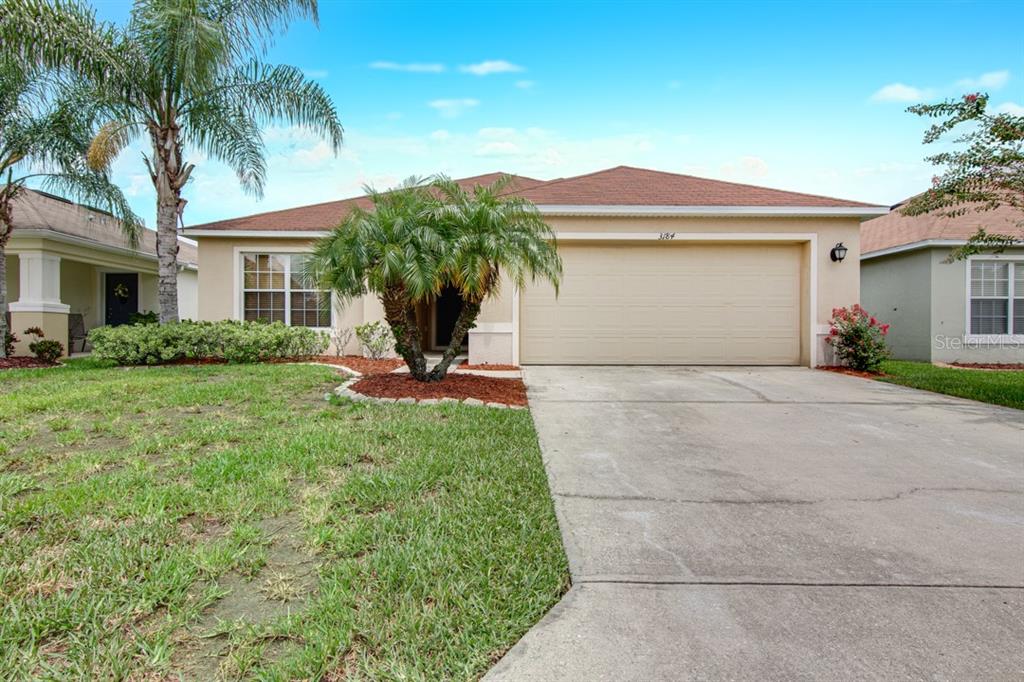 a front view of a house with a yard and palm trees