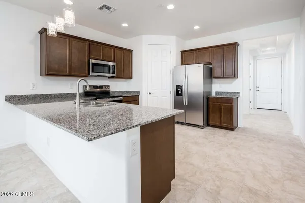 a kitchen with stainless steel appliances granite countertop a refrigerator a stove a sink and a microwave