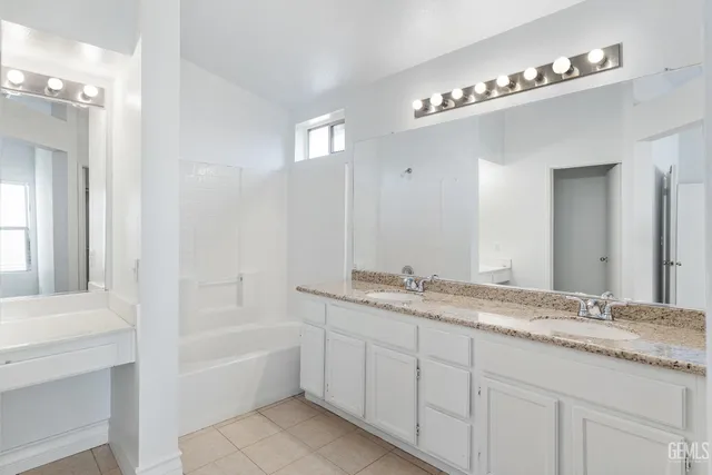 a bathroom with a granite countertop sink a large mirror and a bathtub