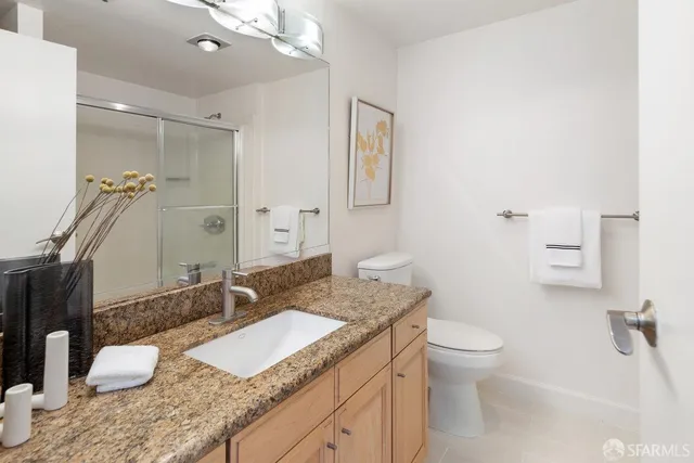a bathroom with a granite countertop sink mirror vanity and toilet
