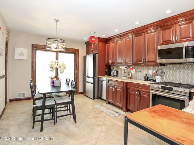 a kitchen with stainless steel appliances kitchen island granite countertop a stove top oven a sink dishwasher and wooden cabinets