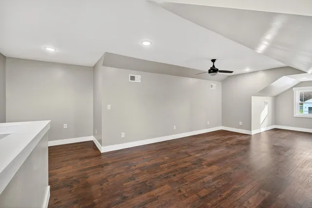 a view of an empty room with wooden floor and a ceiling fan