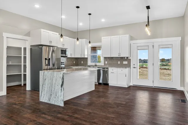 a kitchen with kitchen island granite countertop a stove a refrigerator a sink a center island and wooden floor